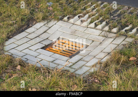 verrostete Kanaldeckel entlang einer Straße Stockfoto