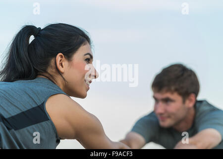 Fitness, Sport, Freundschaft und Lifestyle-Konzept - lächelnde paar machen Yoga-Dehnübungen am Strand am Morgen Stockfoto