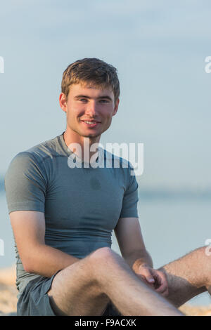 Sportlichen Mann ruht nach dem Training am Strand bei Sonnenuntergang Stockfoto