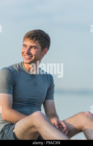 Sportlichen Mann ruht nach dem Training am Strand bei Sonnenuntergang Stockfoto