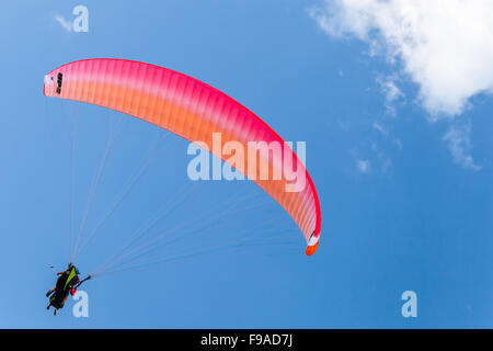 Burgas, Bulgarien - 23. Juli 2014: Gleitschirme in blauer Himmel mit Wolken, Tandem Instruktor und Anfänger unter leuchtend rote parach Stockfoto