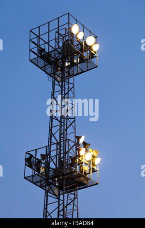 Industrielle leichte Mast mit leuchtenden Lampen am dunkelblauen Himmelshintergrund Stockfoto