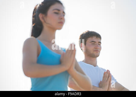 Fitness, Sport, Freundschaft und Lifestyle-Konzept - lächelnde paar machen Meditation Yoga-Übungen am Strand am Morgen Stockfoto