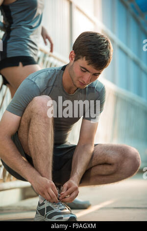 Gut aussehender Mann Schnürung seine Schuhe vor dem Ausführen im freien Stockfoto