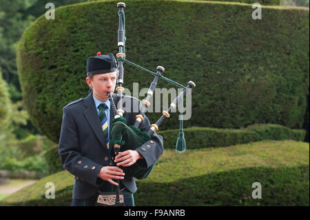 Teen Junge draußen Crathes Castle in Aberdeenshire, Schottland Dudelsack spielen. Stockfoto