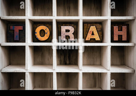 Das Wort "TORAH" Vintage Tinte geschrieben befleckte hölzerne Buchdruck-Typ in einen partitionierten Drucker Schublade. Stockfoto