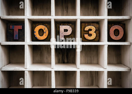 Das Wort "TOP 30" Vintage Tinte geschrieben befleckte hölzerne Buchdruck-Typ in einen partitionierten Drucker Schublade. Stockfoto