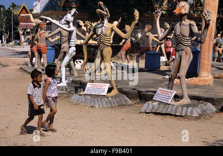 Thailändische Kinder besuchen den hell Garden mit Betonstatuen von Sündern, die als Tiere wiedergekarrt sind. Kitsch-Folk-Kunstskulptur im Wat Wang Saen Suk hell Garden im Tempelgelände, Bang Saen, Chonburi Thailand Stockfoto