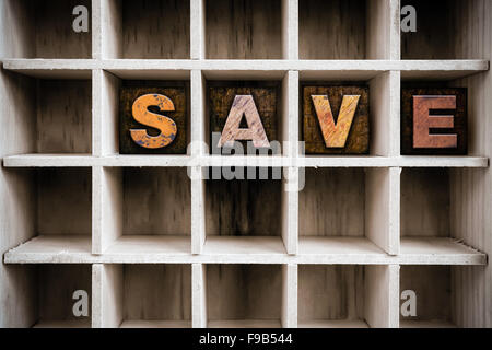 Das Wort "SAVE" in Vintage Tinte befleckte hölzerne Buchdruck-Typ in einen partitionierten Drucker Schublade geschrieben. Stockfoto