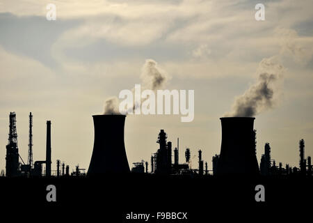 Rauch und Dampf, die sich aus petrochemischen Industrieanlagen Schornsteine Silhouette gegen den Himmel Stockfoto