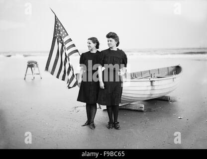 Porträt zweier junger Frauen mit amerikanischer Flagge und Ruderboot am Strand, Atlantic City, New Jersey, USA, 1900 Stockfoto