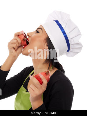 Junge Frau Koch beißen eine in Scheiben geschnittene Granatapfel-Frucht Stockfoto