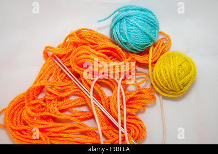 Orange, blue and yellow wool balls and knitting needles on white background Stockfoto