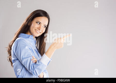 Schöne junge Frau zeigte irgendwo auf einem weißen Hintergrund isoliert Stockfoto