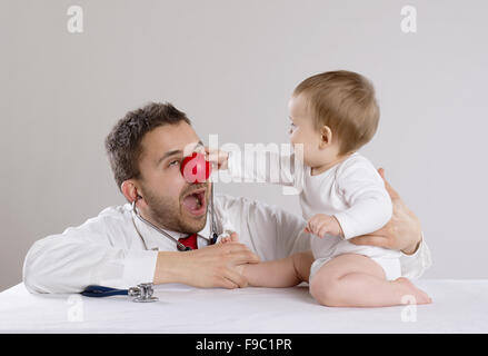 Kinderarzt Arzt mit roter Nase zeigt Baby Stethoskop Stockfoto
