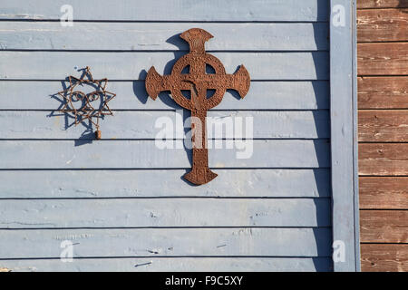 Ein Draht Sonne und Verrostetes Metall Kreuz auf dem Hintergrund von einem blassen blauen Holzverkleidung. Ein Übergang Streifen braun Abstellgleis. Stockfoto