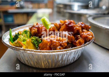 Beliebte chinesische Gericht allgemeine Tsos Hühnchen auf dem Küchentisch in einer Folie Container Stockfoto