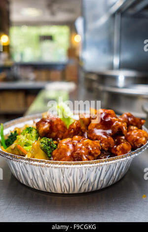 Beliebte chinesische Gericht allgemeine Tsos Hühnchen auf dem Küchentisch in einer Folie Container Stockfoto