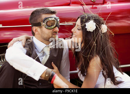 Wunderschöne Braut und Bräutigam Spaß mit roten Retro-Auto in der Natur Stockfoto