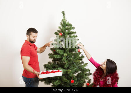 Junges Paar ist Weihnachtsbaum schmücken. Frau ist schwanger. Stockfoto