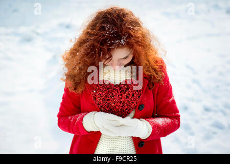 Ein schönes Mädchen mit dem roten Herzen im Schnee Stockfoto