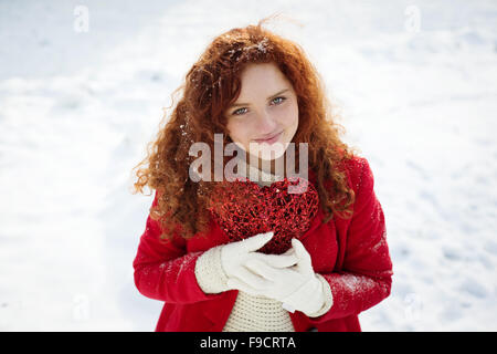 Einsames Mädchen im roten Mantel hält Herz und warten. Stockfoto