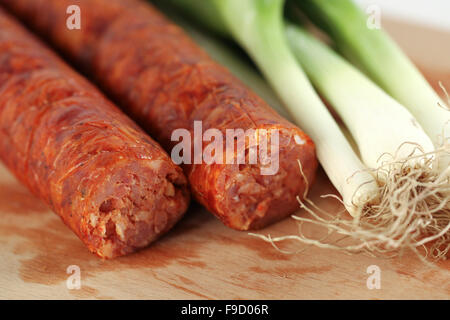 Leckere Wurst mit Zwiebel auf Holzplatte Stockfoto