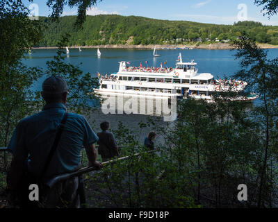 Touristen an den Ufern des Sees Rursee warten auf die Ankunft von einem Passagierschiff in der deutschen Eifel-Nationalpark. Stockfoto