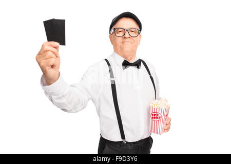 Elegante senior Gentleman hält eine Schachtel mit Popcorn und zwei Tickets isoliert auf weißem Hintergrund Stockfoto