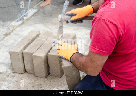 Maurer arbeiten mit Lehmziegeln für eine Mauer zu errichten. Baustelle Stockfoto