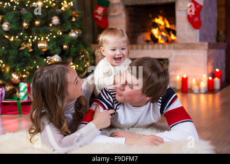 Glückliche junge Eltern und Kind viel Spaß in der Nähe von Weihnachtsbaum zu Hause.  Vater, Mutter und Sohn gemeinsam feiern Neujahr Stockfoto