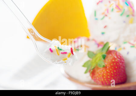 Vanille-Eis im Löffel auf weißem Holz Hintergrund hautnah. Stockfoto