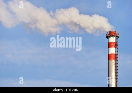 Rauch und Dampf, die sich aus einem petrochemischen Industrieanlagen Schornstein mit einem blauen Himmel im Hintergrund Stockfoto