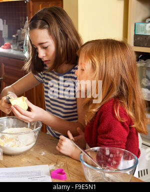 Schneiden die Butter. Eine ältere Schwester schneidet vorsichtig die Butter in das Mehl bereit für den nächsten Schritt bei der Herstellung von Lebkuchen. Stockfoto