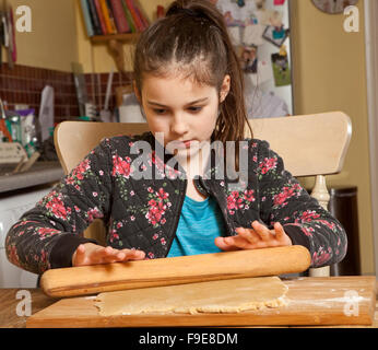 Den Teig ausrollen. Ein junges Mädchen rollt vorsichtig den Teig für das Schneiden in Lebkuchen Formen. Sie konzentriert sich hart Stockfoto