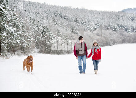 Frau und Mann haben Spaziergang mit Hund in verschneiter Winterlandschaft Stockfoto