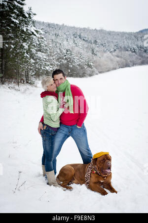 Frau und Mann haben Spaziergang mit Hund in verschneiter Winterlandschaft Stockfoto