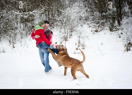 Frau und Mann haben Spaß mit Hund im verschneiten Winterlandschaft Stockfoto