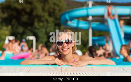 Schöne junge Frau, die Spaß außerhalb im Schwimmbad Stockfoto