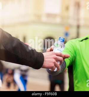 Läufer, die unter eine Flasche Wasser auf das Rasthaus in der Stadt-Wettbewerb Stockfoto
