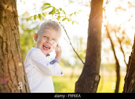 Kleiner Junge spielt und einen Kletterbaum außerhalb in einem park Stockfoto