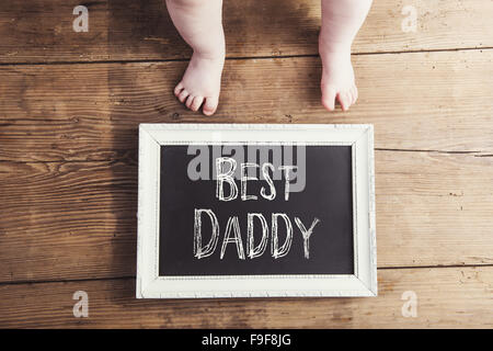 Kleines Baby mit besten Papa melden Sie auf hölzernen Hintergrund Stockfoto