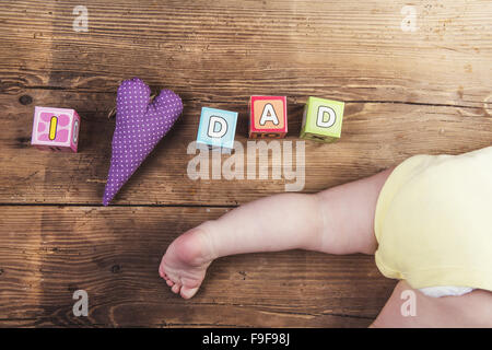 Kleines Baby mit Würfeln mit Papa zu unterzeichnen, auf hölzernen Hintergrund Stockfoto