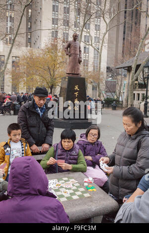 Chinesische spielen Mah-jongg Brettspiele unter Dr. Sun Yat-Sen Statue, Columbus Park, Chinatown, New York City, USA Stockfoto