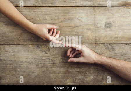 Hände von Mann und Frau zärtlich berühren. Studio auf einem hölzernen Hintergrund erschossen, Ansicht von oben. Stockfoto