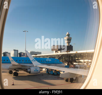 Der Flughafen Schiphol mit KLM Cityhopper PH-EZO Embraer E-190 Flugzeug am Gate und Kontrollturm. Blick vom einen Fensterplatz Stockfoto