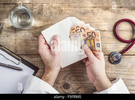 Händen der unkenntlich Arzt Annahme einer Bestechung. Schreibtisch aus Holz Hintergrund. Stockfoto