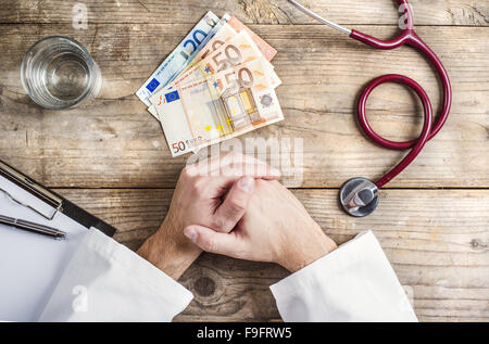 Händen der unkenntlich Arzt Annahme einer Bestechung. Schreibtisch aus Holz Hintergrund. Stockfoto