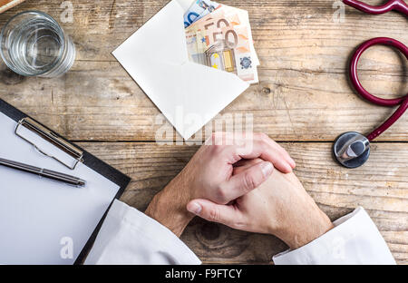 Händen der unkenntlich Arzt Annahme einer Bestechung. Schreibtisch aus Holz Hintergrund. Stockfoto