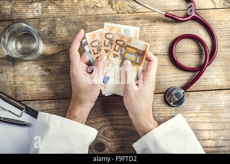 Händen der unkenntlich Arzt Annahme einer Bestechung. Schreibtisch aus Holz Hintergrund. Stockfoto
